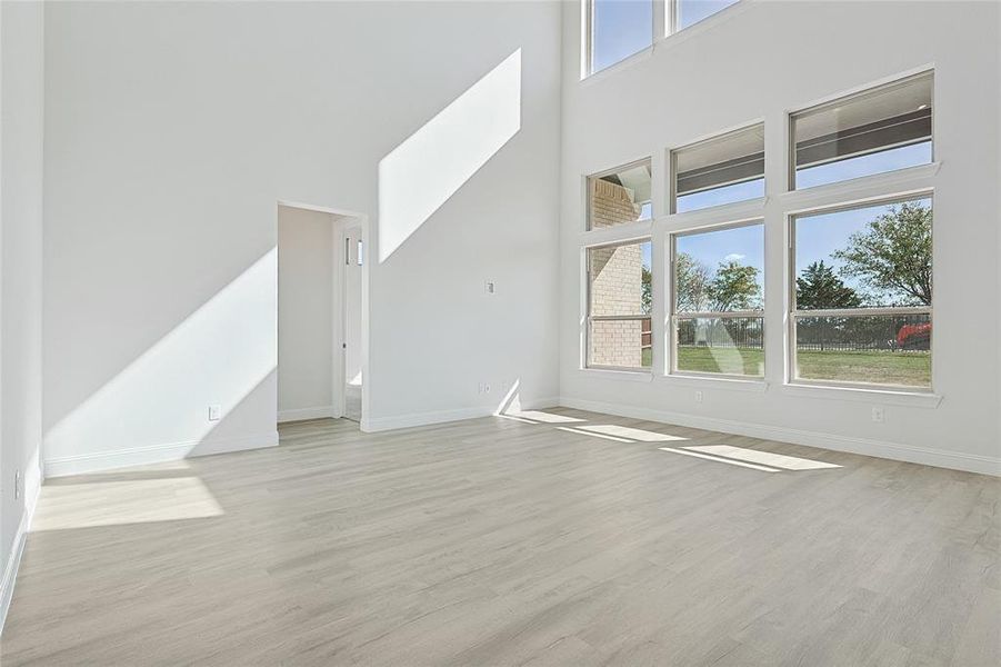 Unfurnished living room featuring a wealth of natural light, a high ceiling, and light hardwood / wood-style floors