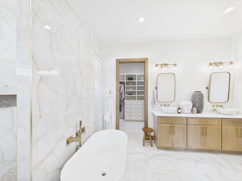 Primary bathroom with soaking tub, dual sinks, and direct access to the walk in closet