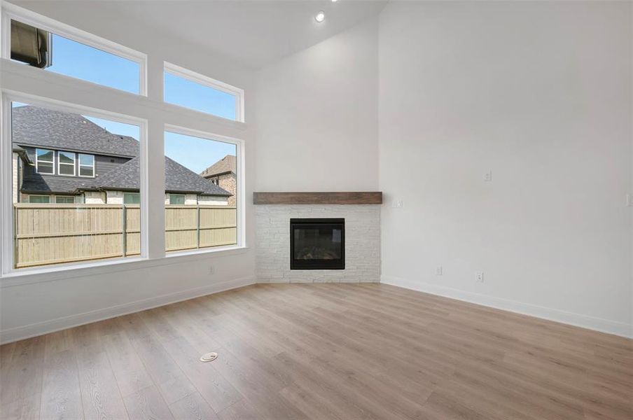 Unfurnished living room featuring a high ceiling, a fireplace, light wood-style flooring, and recessed lighting