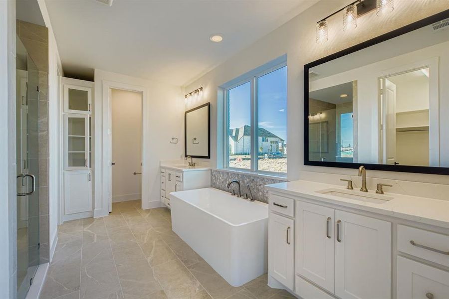 Full bath featuring a freestanding bath, a walk in closet, two vanities, a stall shower, and recessed lighting Full bath featuring a freestanding bath, a walk in closet, two vanities, a stall shower, and recessed lighting