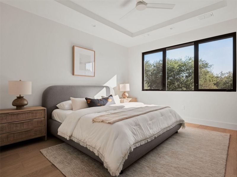 Bedroom featuring a raised ceiling, wood finished floors, and ceiling fan