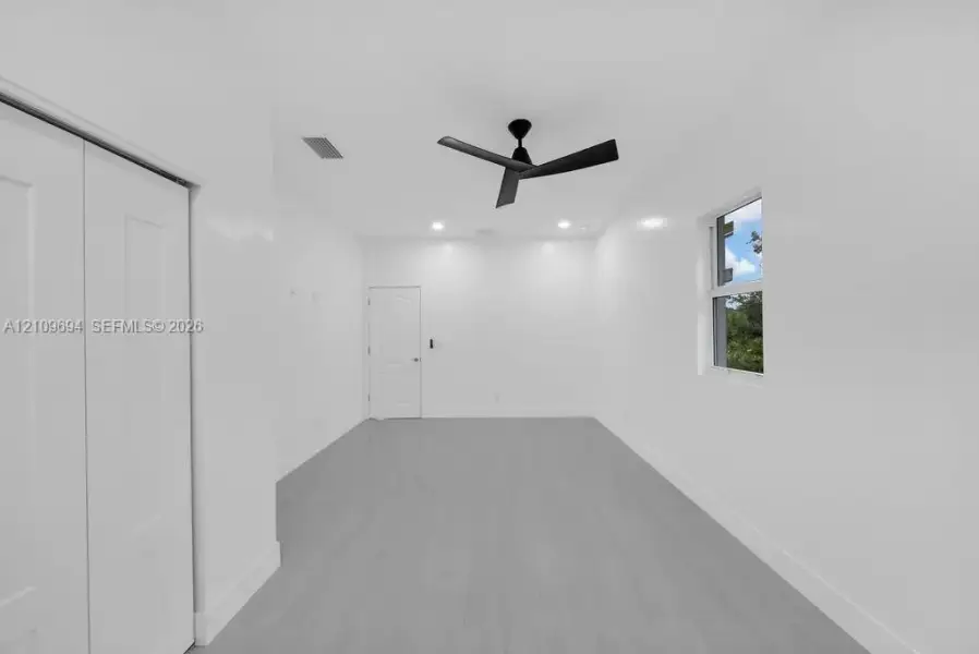 Interior room featuring neutral wall finishes, wood-finish flooring, a matte black ceiling fan, recessed lighting, and a single-panel interior door