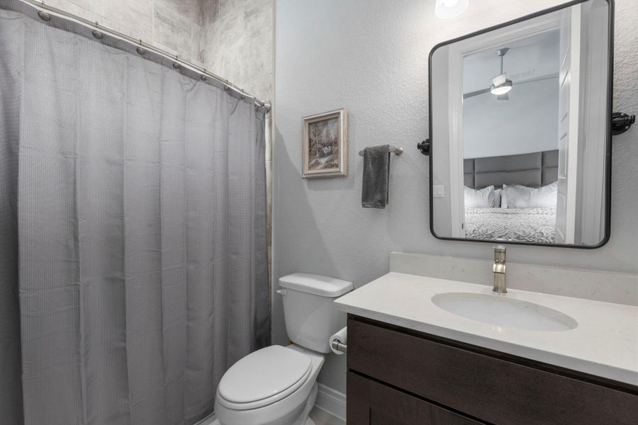 A streamlined vanity with a pristine countertop and modern faucet offers convenient utility within this well-appointed bathroom.