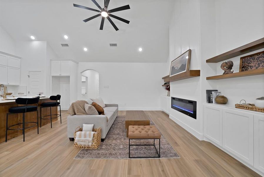 Open-concept living area with wood-finish flooring, a vaulted ceiling, and recessed lighting Open-concept living area with wood-finish flooring, a vaulted ceiling, and recessed lighting