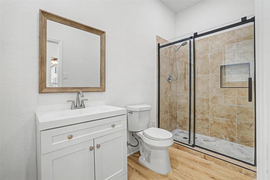 Full bath featuring vanity, light wood finished floors, and a shower stall
