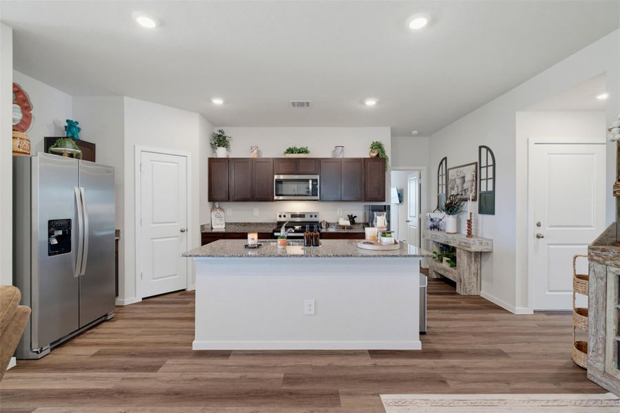 A spacious kitchen features a central island, recessed lighting, and durable wood-look flooring. A spacious kitchen features a central island, recessed lighting, and durable wood-look flooring.