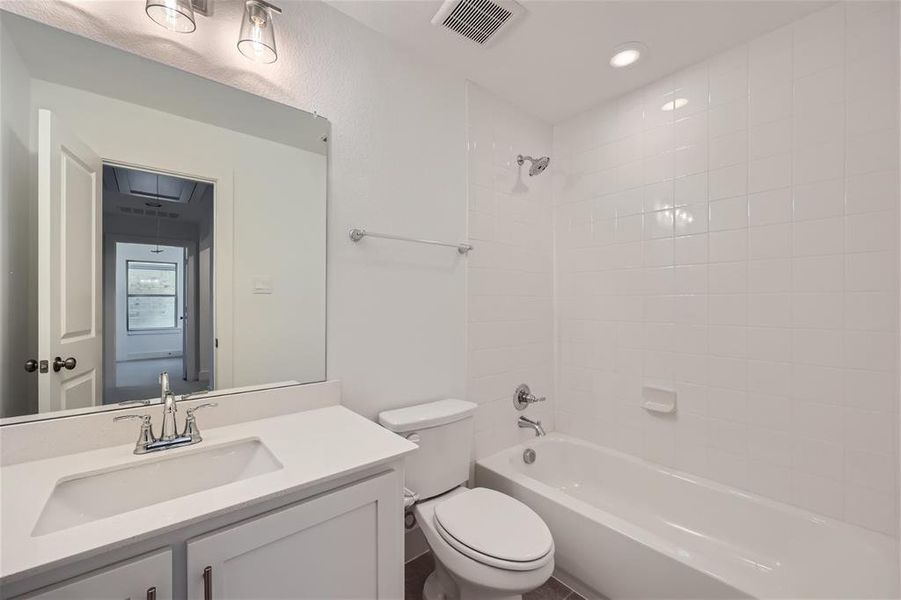 Full bathroom featuring tiled shower / bath, vanity with extensive cabinet space, and toilet