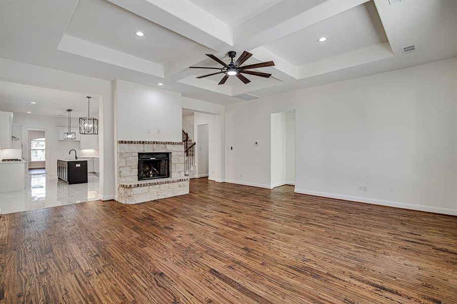 Unfurnished living room with coffered ceiling, hardwood / wood-style flooring, ceiling fan, a fireplace, and beam ceiling