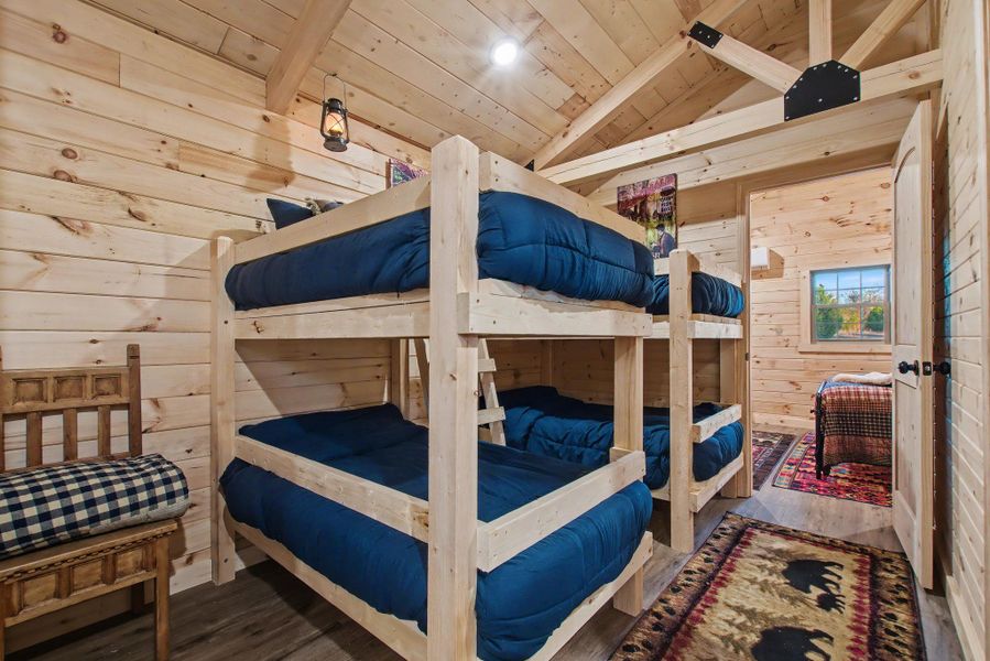 Bedroom with wood walls, wood finished floors, and wood ceiling