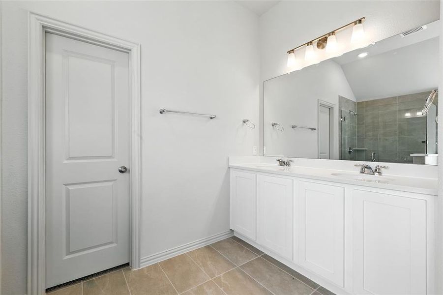Bathroom with light tile patterned floors, a tile shower, and double vanity Bathroom with light tile patterned floors, a tile shower, and double vanity