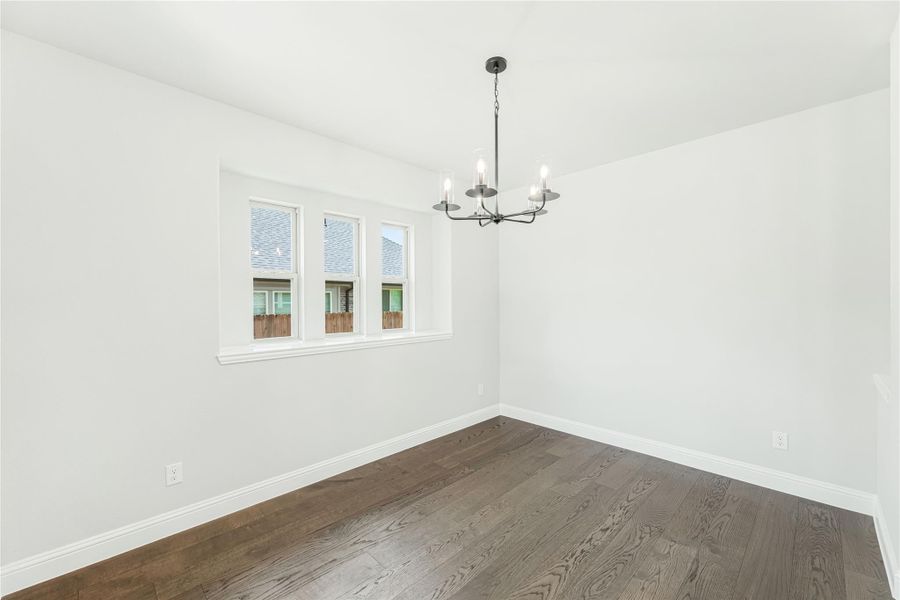 Empty dining room with dark hardwood floors, white walls, and a black chandelier above Empty dining room with dark hardwood floors, white walls, and a black chandelier above