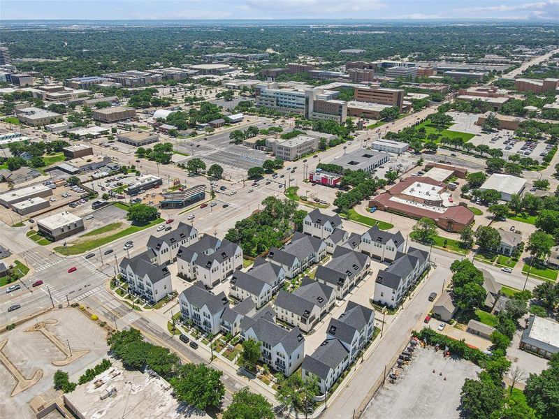 The townhomes are arranged in an elegant pattern, each unit showcasing stylish rooftops and private, gated front yards.