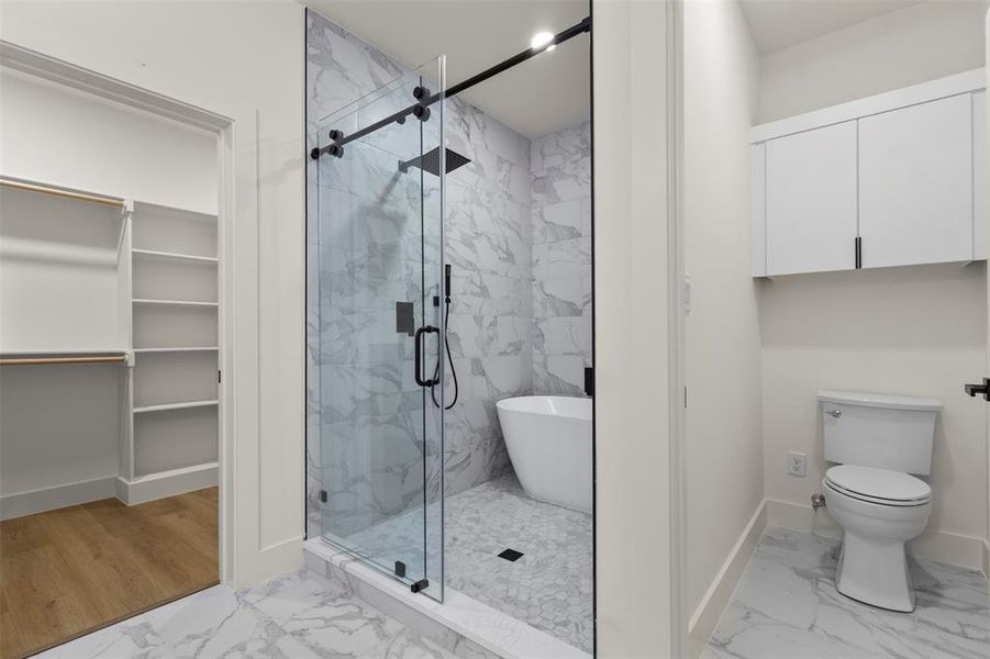 Full bath featuring light marble finish floors, a marble finish shower, a soaking tub, and a walk in closet