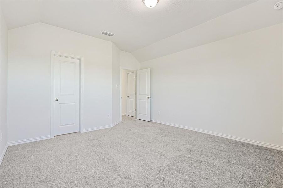Unfurnished bedroom featuring lofted ceiling and carpet