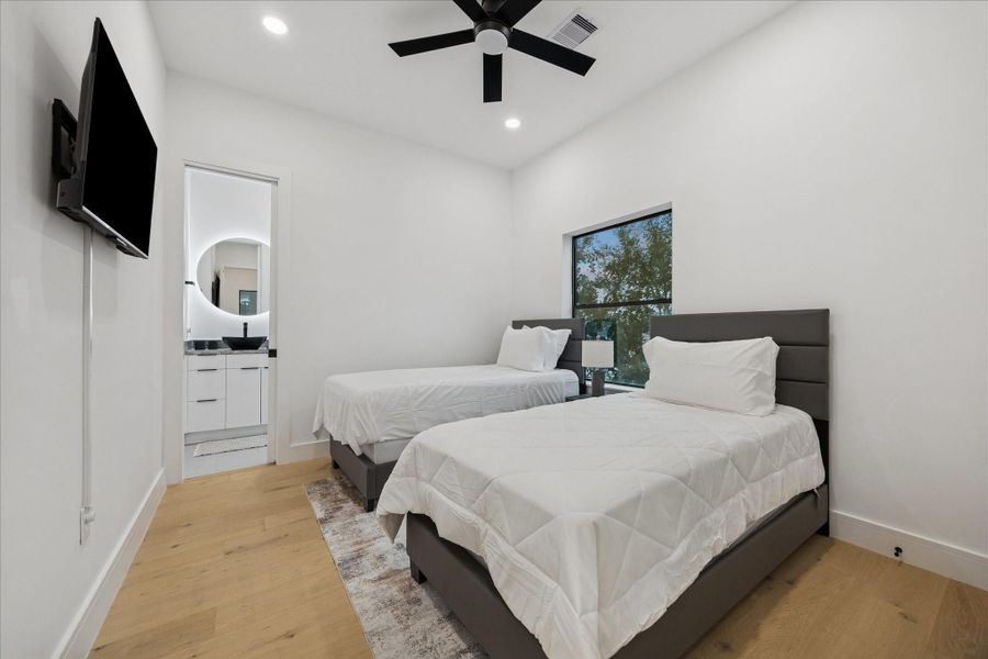 Third-floor bedroom featuring an en-suite full bath, generous natural light, and a comfortable layout well-suited for guests or a private home office.