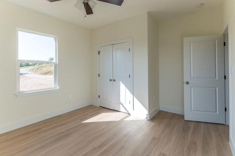 Unfurnished bedroom featuring light wood-style flooring, ceiling fan, and a closet