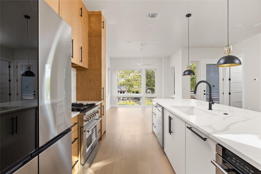 Sleek modern cabinetry and stone countertops anchor this light-filled open kitchen.