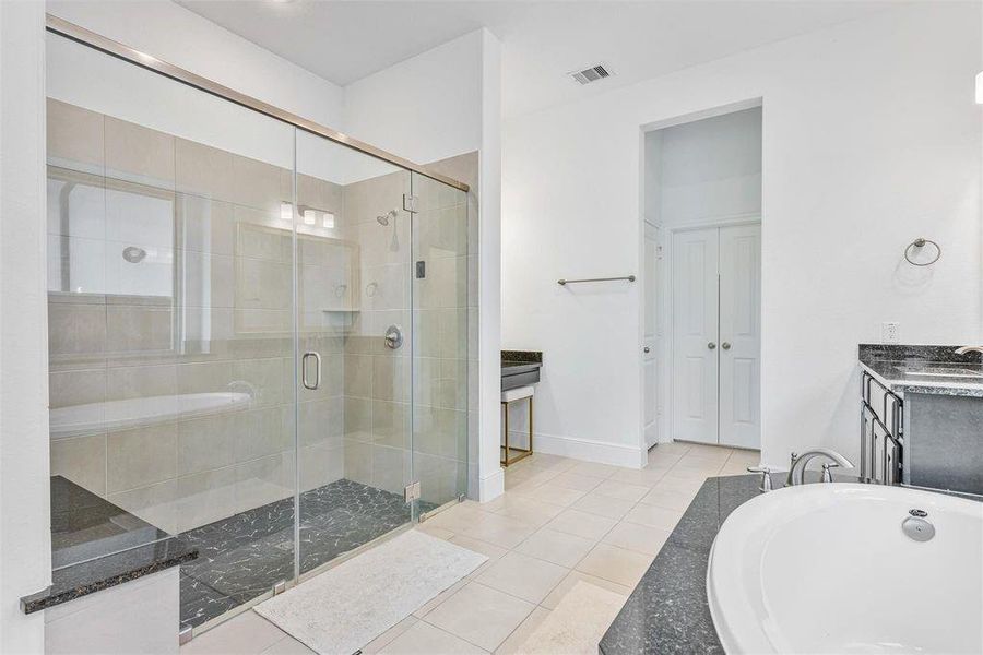 Primary bath boasts separate vanity sinks a nice sized garden tub, a make up vanity, large standing shower with bench, and wonderful natural light.