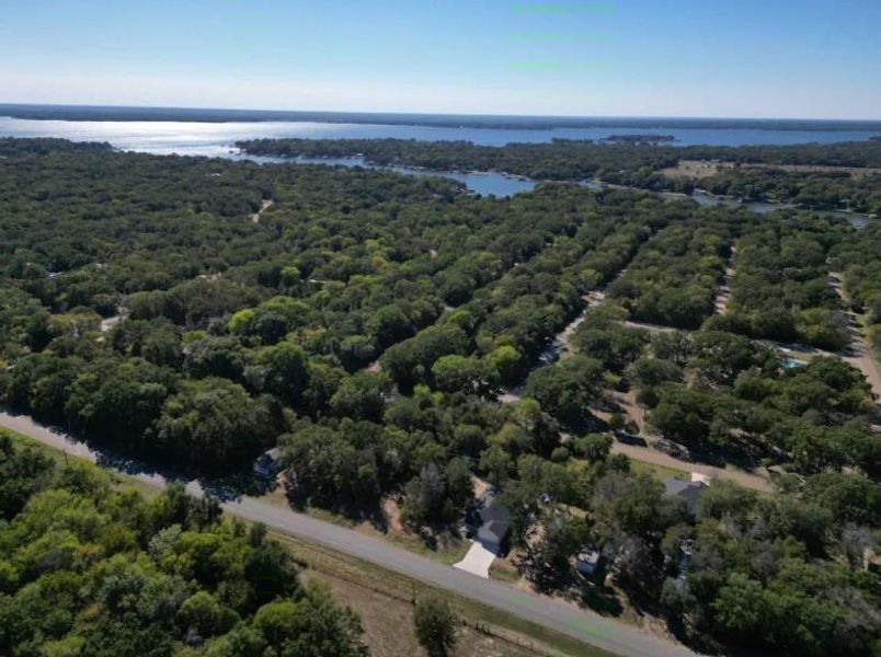 Aerial view of property's location with a heavily wooded area and a large body of water