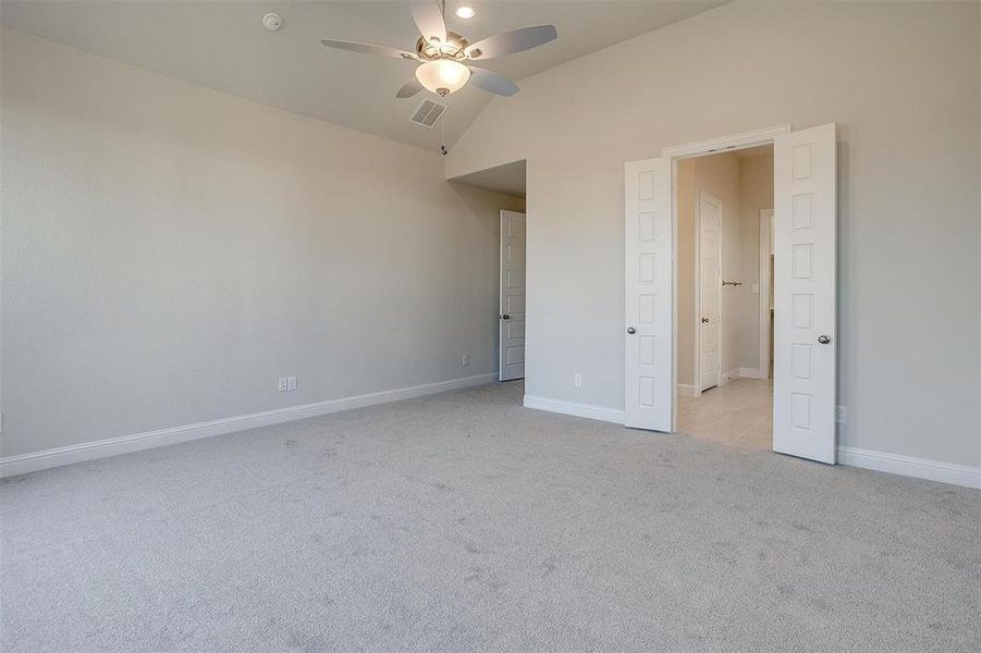 Unfurnished bedroom featuring ceiling fan, light carpet, and lofted ceiling