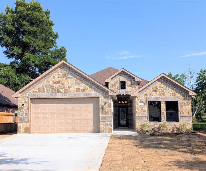 Stone and brick facade with a prominent two-car garage, an arched entryway and glass accented door, with chandelier lighting in patio Stone and brick facade with a prominent two-car garage, an arched entryway and glass accented door, with chandelier lighting in patio