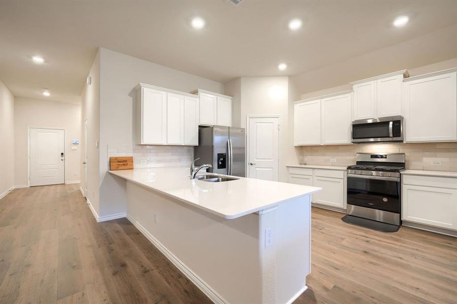 Kitchen with appliances with stainless steel finishes, white cabinets, decorative backsplash, a peninsula, and recessed lighting Kitchen with appliances with stainless steel finishes, white cabinets, decorative backsplash, a peninsula, and recessed lighting