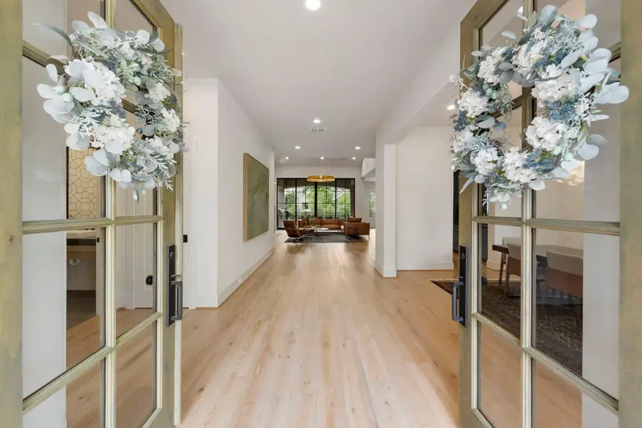 Striking entryway with double glass doors leading to wide-plank wood floors and a light-filled interior that sets the tone for the home.