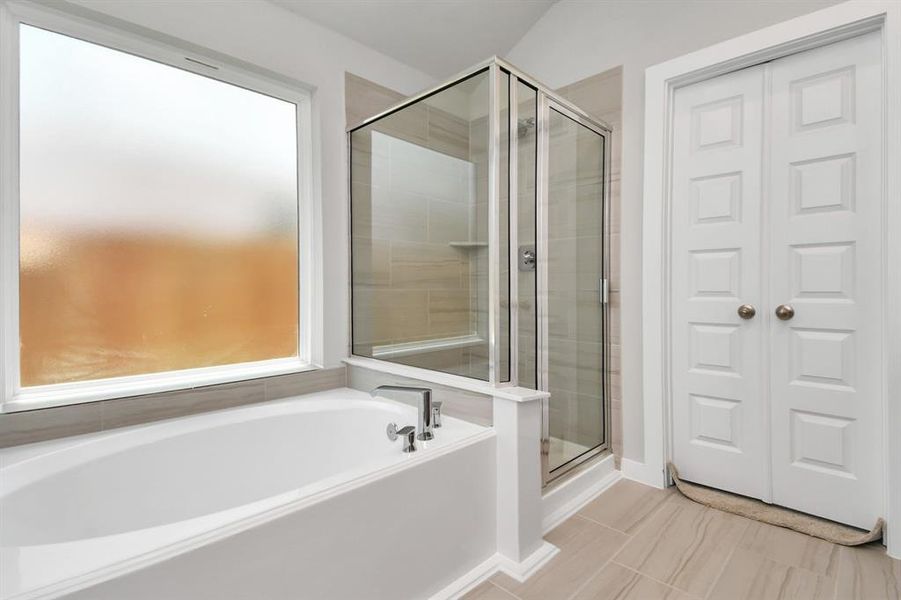 The primary en-suite has a soaking tub to give you that spa experience. The large privacy window allow lots of nature light in the space.  Sample photo of completed home with similar floor plan. Actual colors and selections may vary.