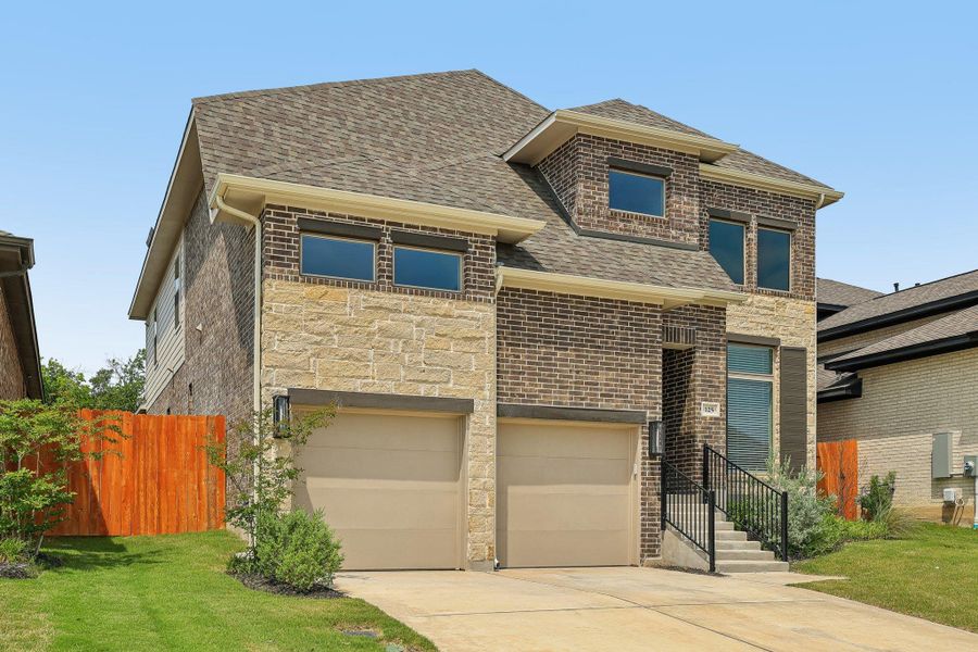 View of front facade featuring a garage, concrete driveway, a shingled roof, stone siding, and brick siding View of front facade featuring a garage, concrete driveway, a shingled roof, stone siding, and brick siding