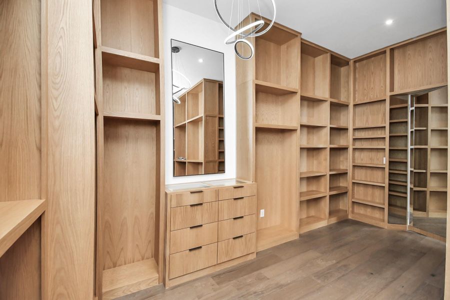 Primary walk in closet with custom cabinetry and ample storage.