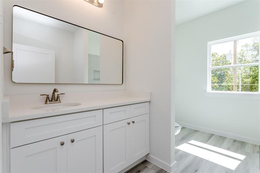 Bathroom featuring wood-type flooring, toilet, and vanity