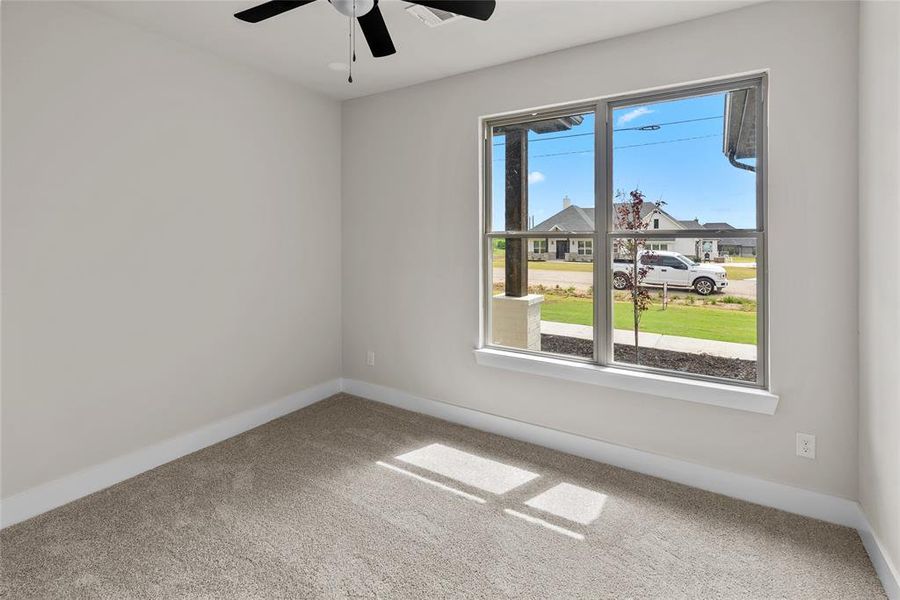 Carpeted spare room featuring ceiling fan and baseboards