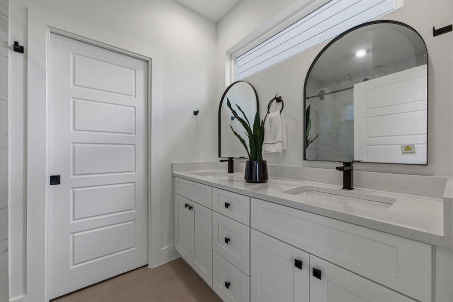 Full bath with double vanity, a marble finish shower, and light tile patterned floors