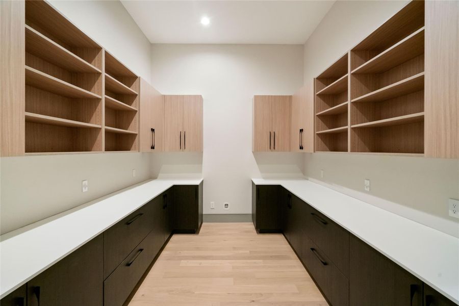 This spacious utility room features ample wooden cabinetry for storage, sleek countertops, and an efficient layout perfect for organizing household essentials.