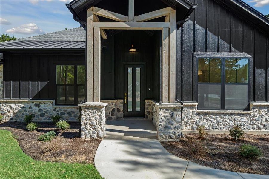 Property entrance featuring stone siding, board and batten siding, a standing seam roof, and a metal roof