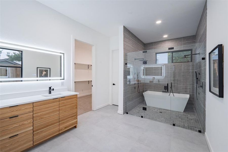 Bathroom featuring tile patterned flooring, plus walk in shower, vanity, and a healthy amount of sunlight