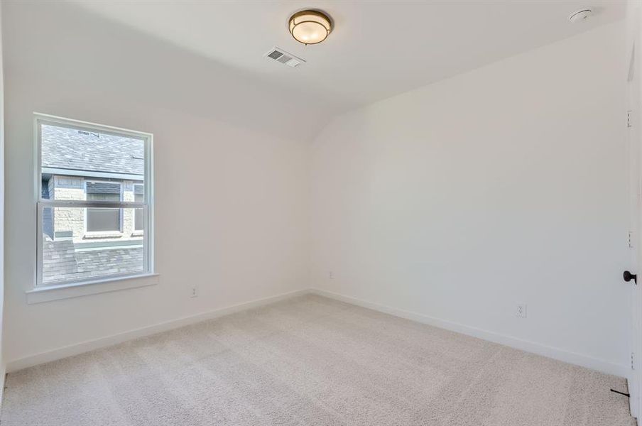 Empty room featuring light carpet and lofted ceiling