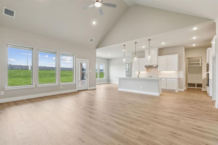 Unfurnished living room featuring high vaulted ceiling, ceiling fan, sink, and light hardwood / wood-style floors