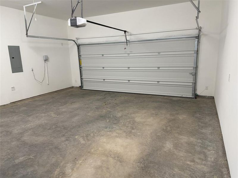 Garage featuring a garage door opener and electric panel