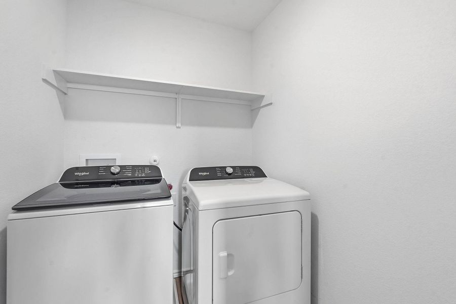 Dedicated laundry area featuring a top-load washing machine, front-load dryer, and an overhead storage shelf Dedicated laundry area featuring a top-load washing machine, front-load dryer, and an overhead storage shelf