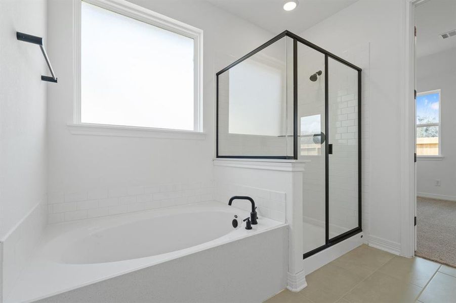 This additional view of your primary bathroom features tile flooring, fresh paint, walk-in shower, a separate garden tub, and a large walk-in closet.