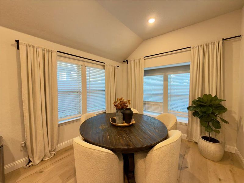 Dining space with vaulted ceiling, light wood finished floors, and recessed lighting