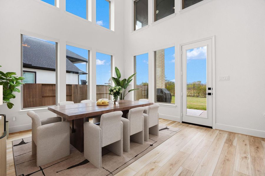 The dining area is filled with natural light and features soaring ceilings and expansive windows.