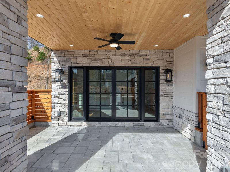 Representative photo from 50 Verde Drive showing the builder’s quality of construction and finish level, including the covered entry, cultured stone, tongue-and-groove wood ceiling, natural gas lanterns, and concrete patio.