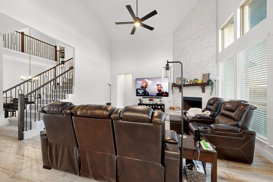 Living room featuring high vaulted ceiling, a chandelier, a stone fireplace, stairway, and ceiling fan Living room featuring high vaulted ceiling, a chandelier, a stone fireplace, stairway, and ceiling fan
