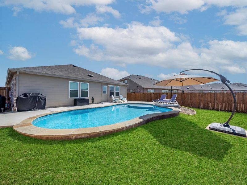 View of swimming pool featuring area for grilling, a fenced backyard, and a patio area