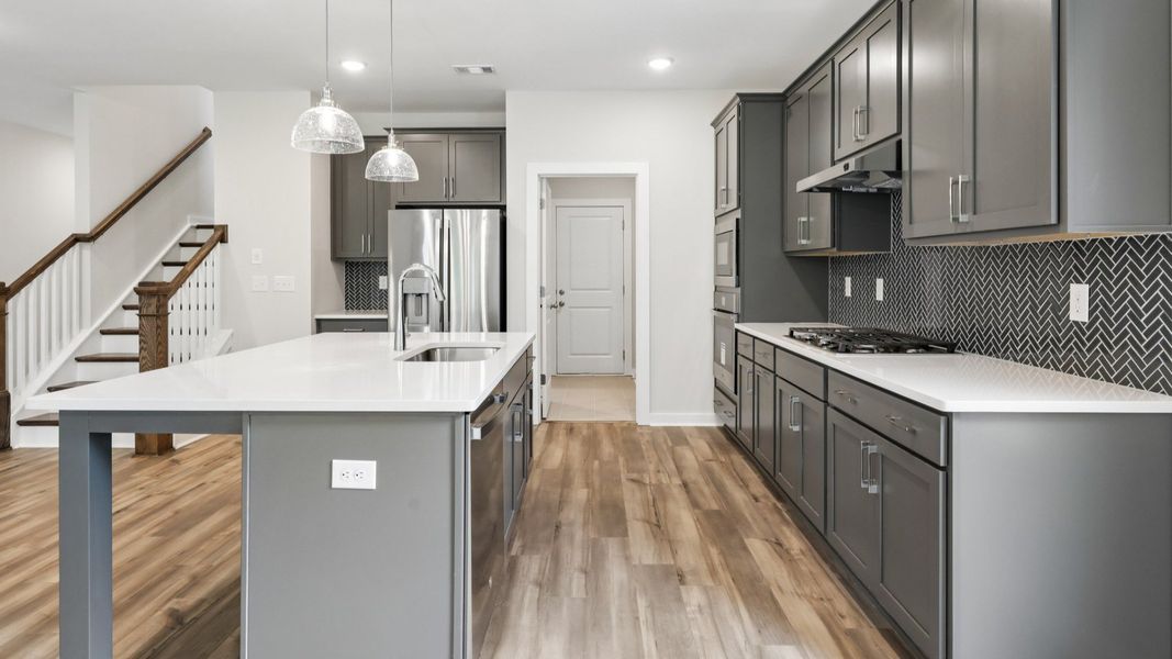 Kitchen with hard surface flooring, quartz countertops, and pendant lighting