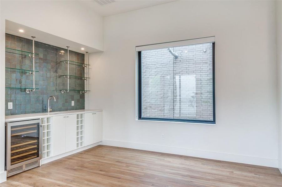 Dining room features a wet bar with glass shelving, plenty of storage cabinets and beverage refridgerator