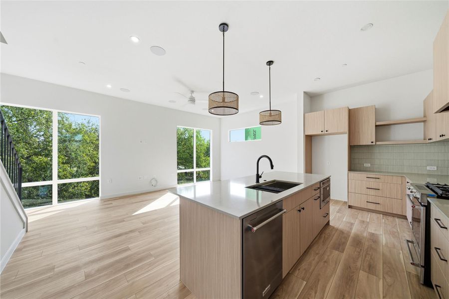 Kitchen with appliances with stainless steel finishes, modern cabinets, light stone counters, light brown cabinets, and light wood finished floors Kitchen with appliances with stainless steel finishes, modern cabinets, light stone counters, light brown cabinets, and light wood finished floors