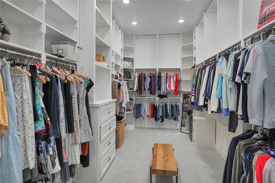 Spacious walk-in closet featuring extensive built-in shelving, multiple hanging rods, recessed lighting, and integrated drawer storage